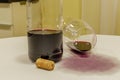 Red wine spilled from glass over white tablecloth with bottle an