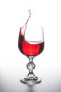 Red wine splashing in wine glass on light background Royalty Free Stock Photo