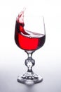 Red wine splashing in wine glass on light background Royalty Free Stock Photo