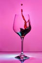 Red wine splashing in a glass on a pink background Royalty Free Stock Photo