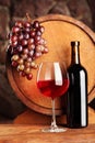 Red wine.Still life with glass and bottle of red wine, grapes and barrel.Selective focus.Wine cellar atmosphere. Royalty Free Stock Photo