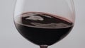 Red wine swirling glass slow motion. Gourmet alcohol drink waving in wineglass.