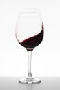 Red wine swirling in glass on white background