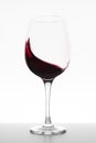 Red wine swirling in glass on white background