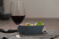 Red wine in thin wine glass with salad in blue bowl