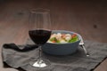 Red wine in thin wine glass with salad in blue bowl