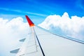 Red wing of the aircraft view from airplane window seat flying in the blue sky with white clouds background, copy space Royalty Free Stock Photo