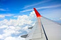 Red wing of the aircraft view from airplane window seat flying in the blue sky with white clouds background, copy space Royalty Free Stock Photo