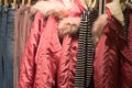 Red winter coats with fur and hood with other clothes hanging on hangers Royalty Free Stock Photo