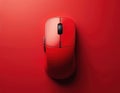 Red wireless computer mouse isolated on plain red background. Top view of modern tech gadget for work and play. Digital device Royalty Free Stock Photo
