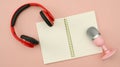 Red wireless headphone and microphone and empty notepad on pink background. Technology and audio equipment concept Royalty Free Stock Photo