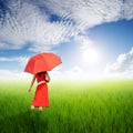 Red Woman holding umbrella in green rice fields in sun sky Royalty Free Stock Photo