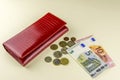 Red woman wallet. Banknotes ten and five euros. A few coins. Beige background. Royalty Free Stock Photo