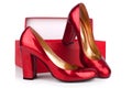 Red women`s high-heeled shoes patent leather and red box on a white background close up