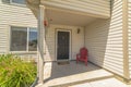 Red wooden armchair by the brown door at the small front porch of a home Royalty Free Stock Photo