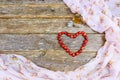 Red wooden beads laid out the shape of a heart on an old wooden table