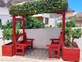 Red wooden bench on pedestrian street with flower pots in rural town. Architecture and urban furniture