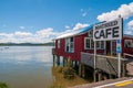 Red wooden Boatshed Cafe on the Hokianga River under blue cloudy sky in New Zealand