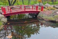 A red wooden bridge at the Japanese Garden inside the Kyoto Park in Kyiv. bridge reflected in the lake water Royalty Free Stock Photo