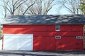 Red wooden building with two white garage doors. Royalty Free Stock Photo