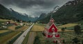 Red wooden church of Olden with road in the fjord Nordfjord in summer in Norway from above