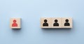 Red wooden cube with person icon stand out from the crowd on blue background. Dissenting opinion, divergent views and different