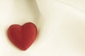 Red wooden decorative heart on white silk background. Royalty Free Stock Photo