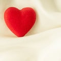 Red wooden decorative heart on white silk background. Royalty Free Stock Photo