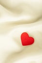 Red wooden decorative heart on white silk background. Royalty Free Stock Photo