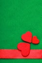 Red wooden decorative hearts on green cloth background Royalty Free Stock Photo