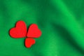 Red wooden decorative hearts on green folds background. Royalty Free Stock Photo