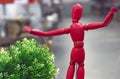 Red wooden doll Gestalta next to a green plant