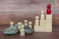 Red wooden doll on top of wooden block with others having to face challenges along the way. Royalty Free Stock Photo