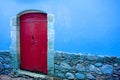 Red wooden door on blue wall of an old building Royalty Free Stock Photo
