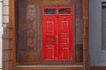 Red wooden door on a rusty brown building wall Royalty Free Stock Photo