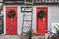 Red wooden doors in the backyard decorated with Christmas wreath Royalty Free Stock Photo