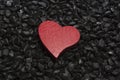 Red wooden heart on a black pebble background. Royalty Free Stock Photo