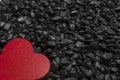 Red wooden heart on a black pebble background. Royalty Free Stock Photo