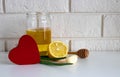 A red wooden heart and natural cold remedies on a white table on a brick background. Garlic, honey, lemon, aloe folk Royalty Free Stock Photo