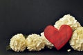 Red wooden heart ornament and snowball flowers on black background with copy space