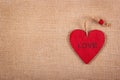 Red wooden heart pendant on a natural linen background. A wooden valentine on a natural background. Backgrounds and textures.