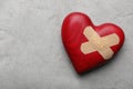 Red wooden heart with sticking plasters on light grey stone table, top view. Space for text Royalty Free Stock Photo