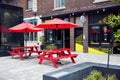 Red wooden picnic benches and picnic tables with umbrellas on the street in front of a cafe in Montreal, Canada Royalty Free Stock Photo
