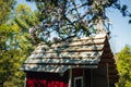 Red wooden playing hut for children with blooming apple trees in the garden in spring