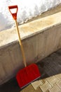 Red wooden shovel leaning against the wall