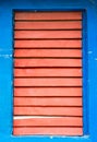 Red wooden shutters closed on window on blue wall Royalty Free Stock Photo