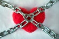 Red wool heart locked with metal chain on white bed sheet