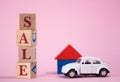 Red word SALE lined with wooden cubes and toy white car and house, on pink background with space for text. Concept of Royalty Free Stock Photo