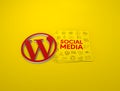 Red WordPress Logo and Social Media papers against a yellow background