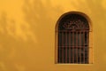 Red wrought iron decorated window on vivid yellow outer wall Royalty Free Stock Photo